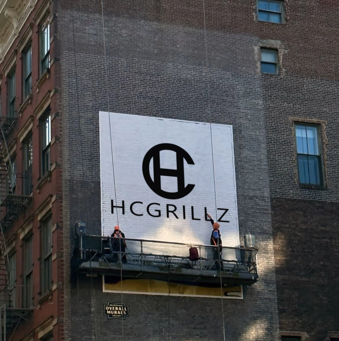 HC Grillz logo being painted on a building